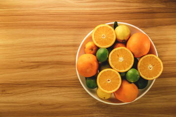 Upper view on citrus fruits on white plate and wooden table