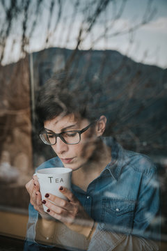 Chica mirando por la ventana con el t&eacute;