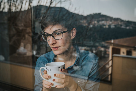 Chica mirando por la ventana con el t&eacute;