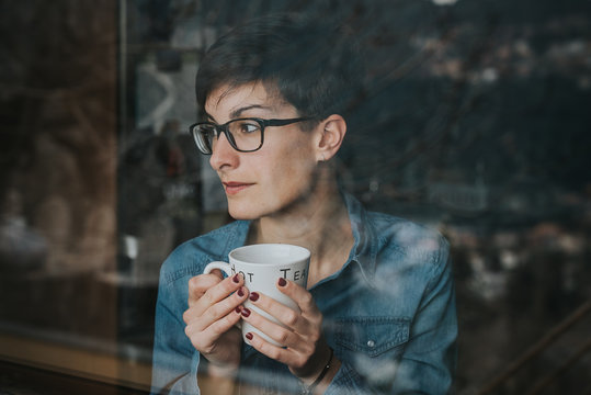 Chica mirando por la ventana con el t&eacute;