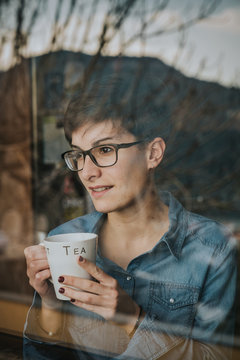 Chica mirando por la ventana con el t&eacute;