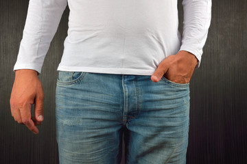 Young man with left hand in the pocket of his blue jeans, wearing white blank t-shirt, standing in a studio. Clothing design concept