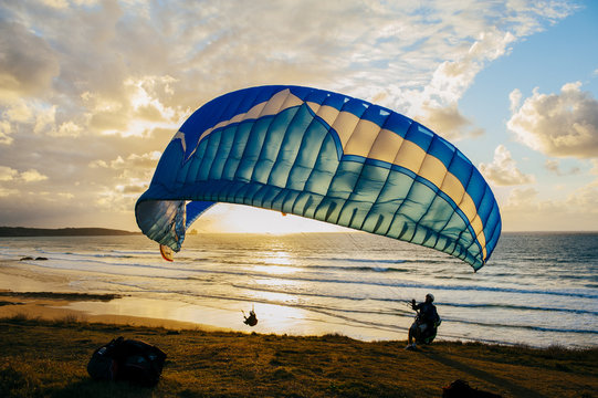 Silhouette of person flying on the parachute over the sea in sunset lights.