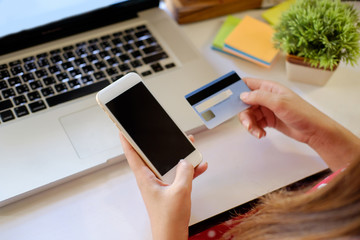 Female hands holding a credit card and using Smartphone for online shopping