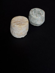 Two small dry cheeses isolated on black background