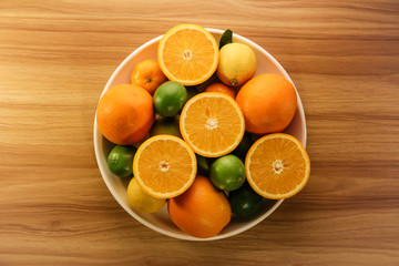Oranges and citrus fruits on white plate on table