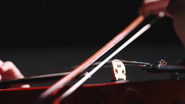 Young Woman playing violin over dark background. backlight Closeup, slow motion