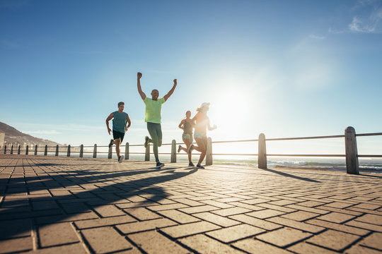 Group of young people running along seaside