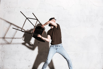 Hipster in snap back throws chair aside