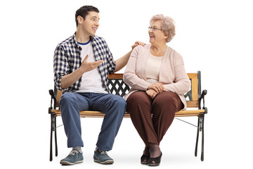 Young man and elderly woman sitting on bench and talking