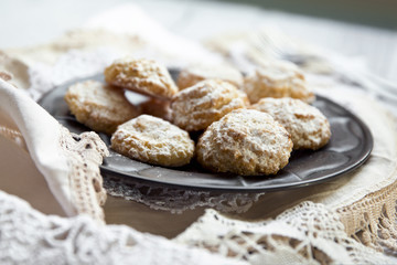 Coconut biscuits with icing sugar over pewter plate