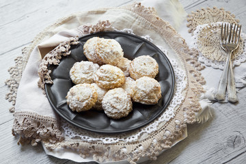 Coconut biscuits with icing sugar over pewter plate