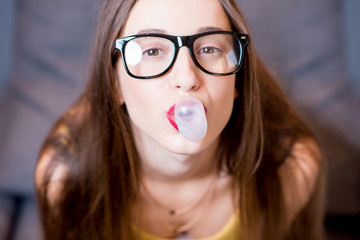 Young woman blowing up a bubble gum indoors