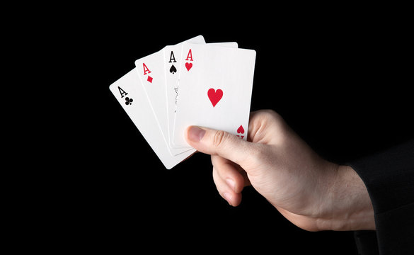 human hand holding four aces