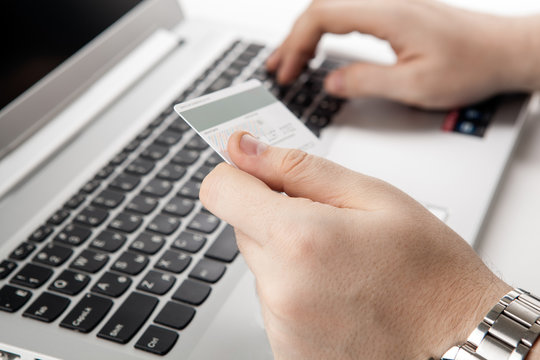 Hands holding a credit card and using laptop computer