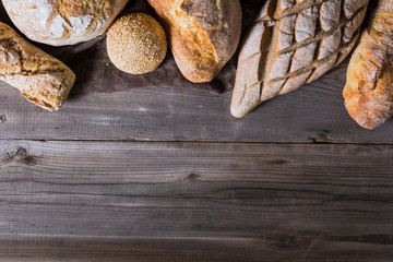 Several types of fresh bread lying on an old wooden table