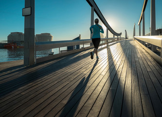 Woman running on the bridge under sunlight.