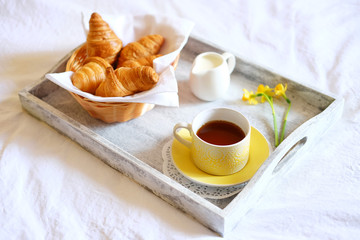 Breakfast in bed. Gray wooden tray with croissants and tea.