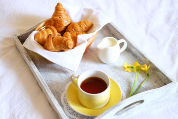 Breakfast in bed. Gray wooden tray with croissants and tea.