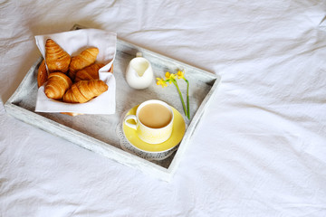 Breakfast in bed. Gray wooden tray with croissants and tea.