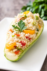 Stuffed zucchini with quinoa and vegetables on wooden background
