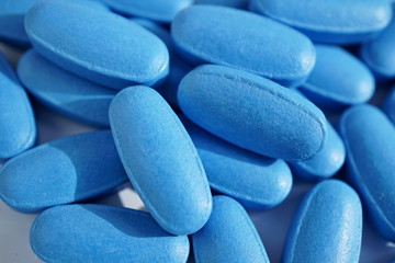 Isolated heap of blue oval pills as a symbol of medicine, healing and pharmacy  - obrazy, fototapety, plakaty