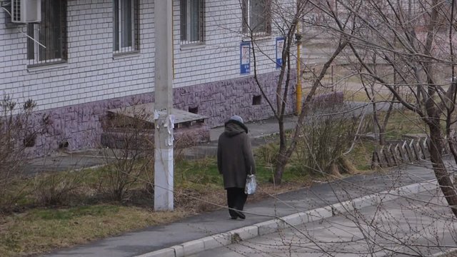 Lonely old woman walking on a sidewalk