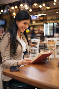Beautiful woman having coffee break,reading book in cafe