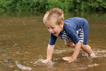 Little boy trying to catch a fish in the middle of stream