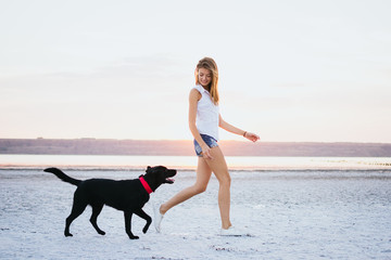 Young female walking with labrador retriever dog on the beach at sunset - 138342805