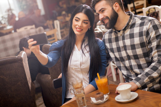 Couple taking selfie with camera phone in cafe