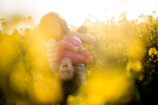 Mom and daughter enjoying outdoors, rapeseed field. Having fun together.