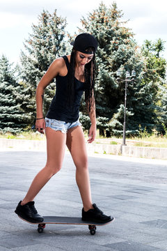 stylish girl in sexy shorts with a skateboard outdoors
