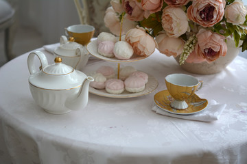 На кухонном столе стоит чайник, чашки и сладости
