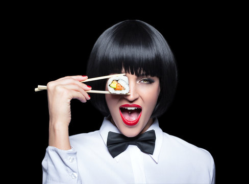 Young woman holding sushi in front of eye