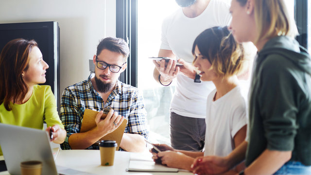 Group of young managers is discussing new business ideas during online meeting with the partners. Project manager is presenting new project to the team of designers by using a portable computer.