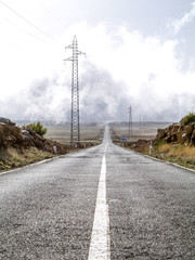 Straight street with power poles ending in the clouds, Portugal,