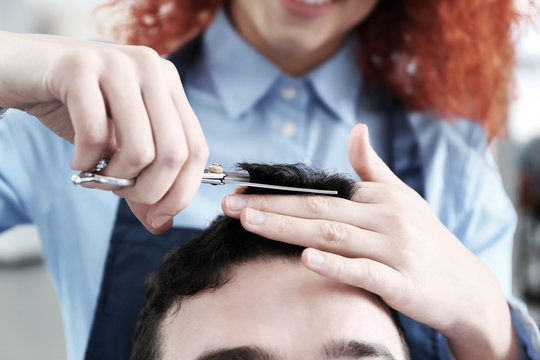 Professional hairdresser making stylish haircut for man