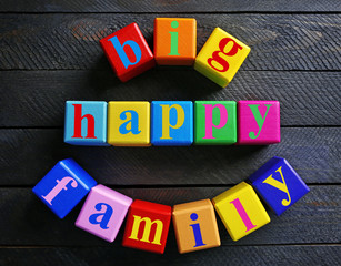 Colorful cubes with text BIG HAPPY FAMILY on wooden background