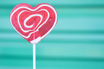 Valentines day and love concept.Red heart shape lollipop with cyan background.