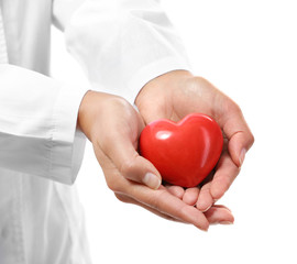 Red plastic heart in female hands on white background, closeup