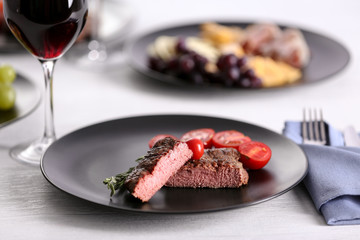 Grilled steak and appetizers with wine on table
