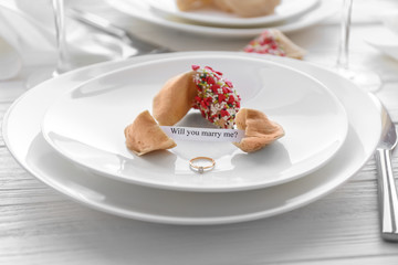 Offer of marriage with fortune cookies and ring on white plate closeup