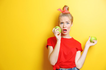 Young beautiful woman with apples on yellow background