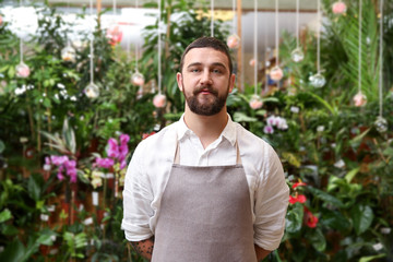 Handsome bearded florist in greenhouse