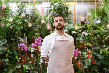 Handsome bearded florist in greenhouse