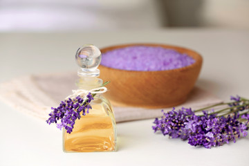 Obraz na płótnie Canvas Bottle of essential oil with lavender and sea salt on background