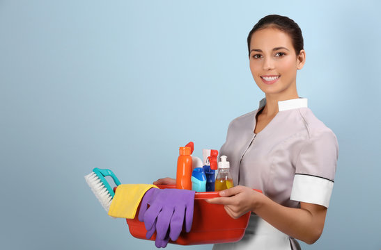 Hotel Female Chambermaid Holding Cleaning Supplies On Color Background