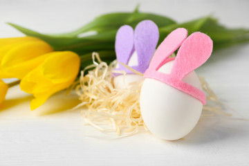 Obraz na płótnie Canvas Easter eggs with bunny ears on white wooden table