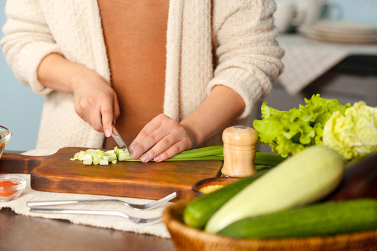 Female hands cutting vegetables at table in kitchen